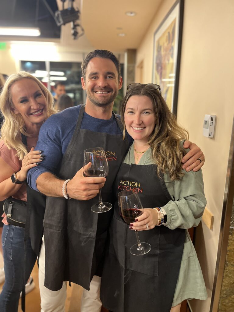 Three employees with aprons, holding wine