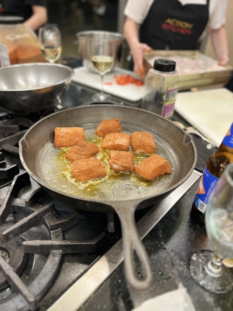 Nine pieces of meat being fried in a steel frying pan
