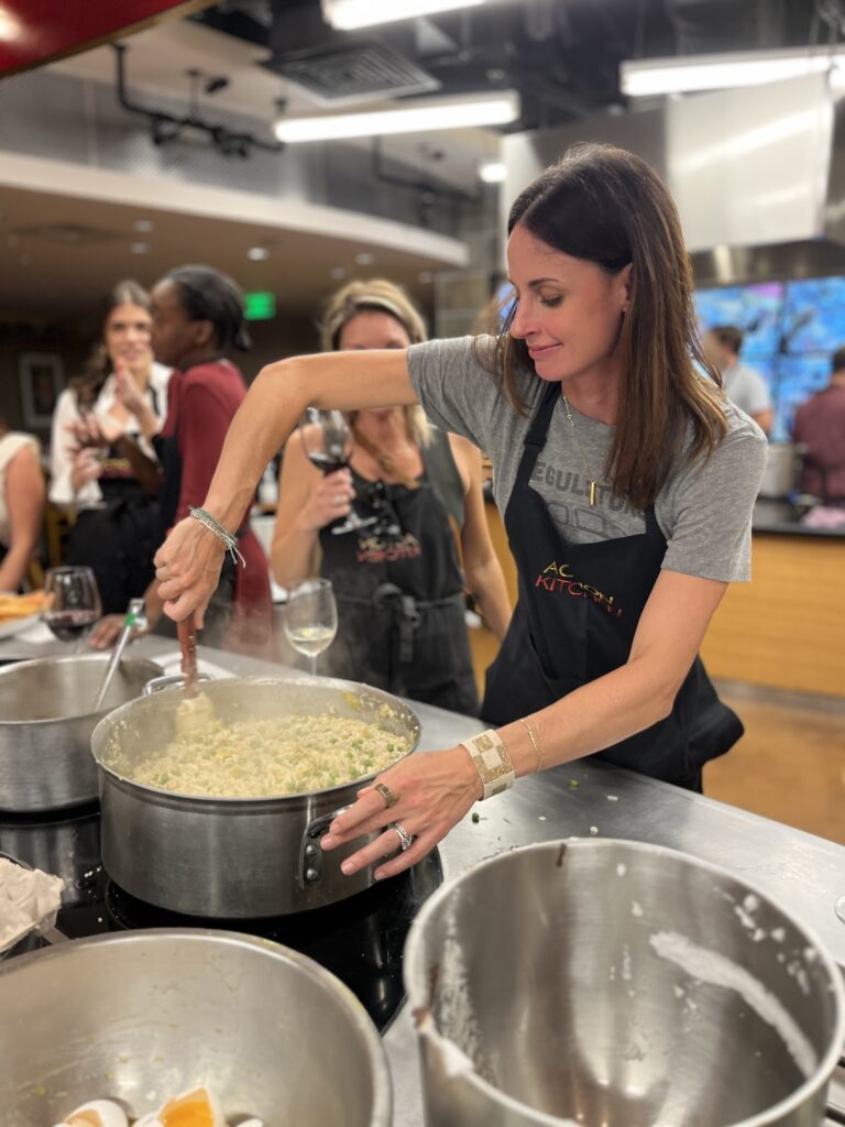 A person mixing soup while two other people look on